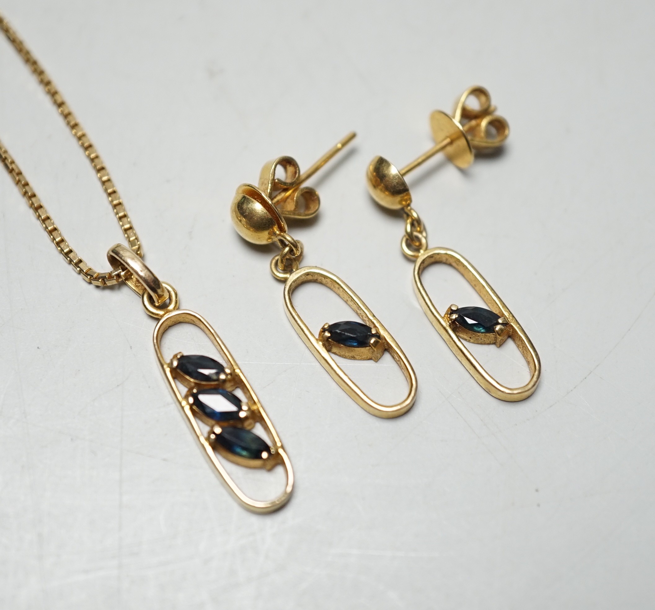 A modern 585 yellow metal and three stone sapphire set pendant necklace, overall 46cm necklace and a pair of matching earrings